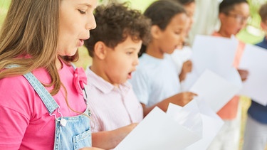 Kinder schauen auf Noten und singen | Bild: picture-alliance/dpa