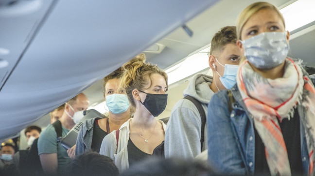 Passagiere stehen in einem Flugzeug mit Mund-Nase-Schutz | Bildquelle: picture alliance/TT NEWS AGENCY/Adam Ihse