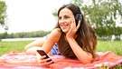 Eine Frau hört im Park über Kopfhörer Musik. | Bild: picture alliance / dpa Themendienst | Tobias Hase