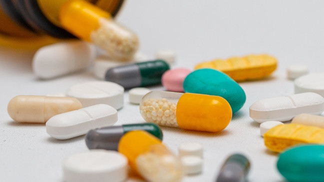 Aus einer Medikamentendose kullern Tabletten in verschiedenen Farben | Bildquelle: picture-alliance/dpa