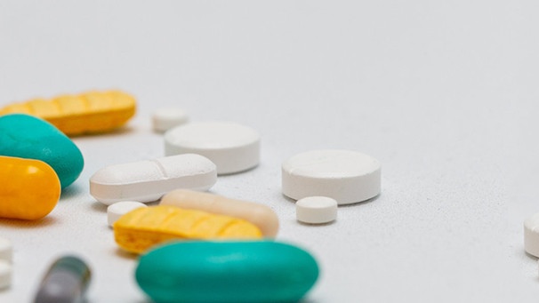 Aus einer Medikamentendose kullern Tabletten in verschiedenen Farben | Bild: picture-alliance/dpa