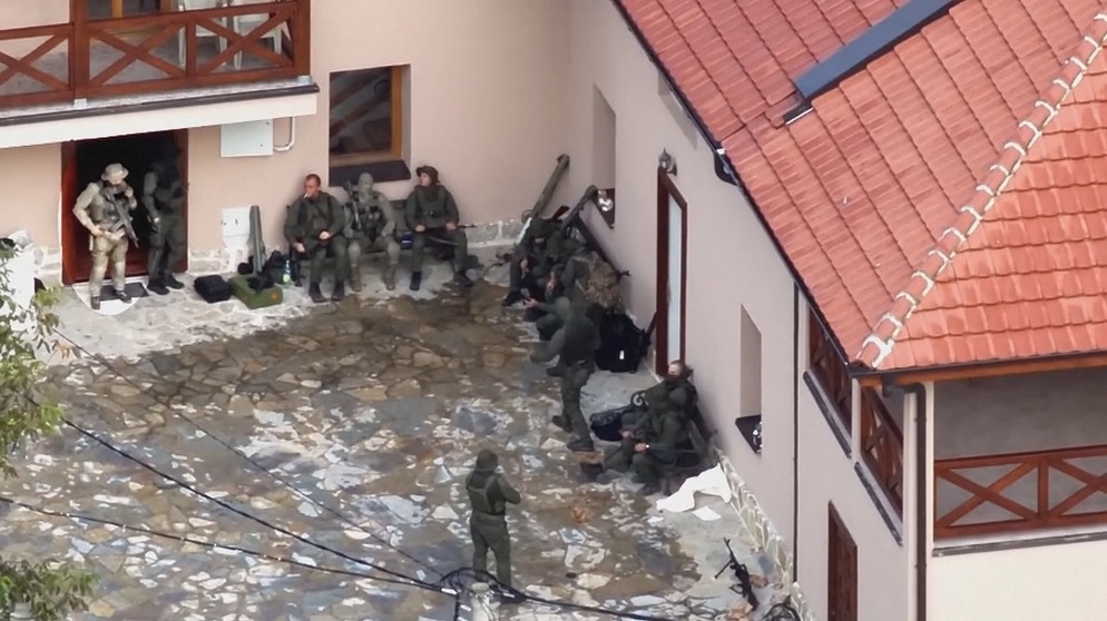 Militärisch ausgerüstete Personen im Innenhof eines Hauses | Bildquelle: BR