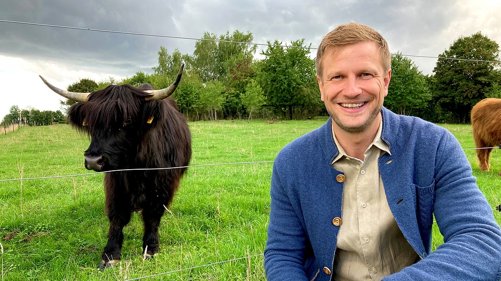 Moderator Florian Kienast, im Hintergrund Biorinder auf der Weide | Bildquelle: BR