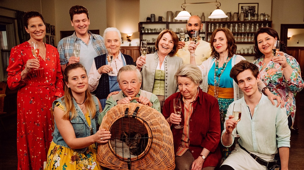 Dahoam is Dahoam: Lansing nimmt Abschied von Margot und Gerstl. Hintere Reihe (von links): Annalena (Heidrun Gärtner), Gregor (Markus Baumeister), Theresa (Ursula Erber), Rosi (Brigitte Walbrun), Pfarrer Naveen (Markus Subramaniam), Doro (Marion Niederländer), Monika (Christine Reimer). Vordere Reihe (von links): Sarah (Sophie Reiml), Gerstl (Gerd Lohmeyer), Margot (Sarah Camp), Joschi (Adrian Bräunig). | Bildquelle: BR/Nadya Jakobs
