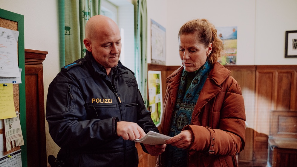 Dahoam is Dahoam: Polizist Haas (Michael Dietmayr, KLD) macht Annalena (Heidrun Gärtner) darauf aufmerksam, dass Betrugsdelikte im digitalen Bereich auf dem Vormarsch sind. | Bildquelle: BR/Nadya Jakobs
