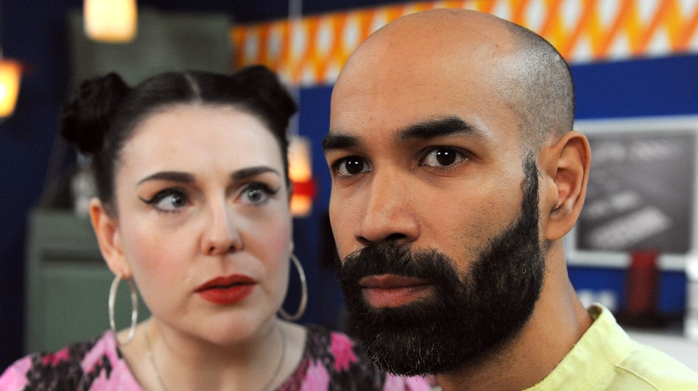 Dahoam is Dahoam: Naveen (Markus Subramaniam) ist entschlossen, Vater zu werden, auch wenn er dann auf sein Amt als katholischer Pfarrer verzichten müsste. Mit Tina (Anita Eichhorn). | Bildquelle: BR/Marco Orlando Pichler