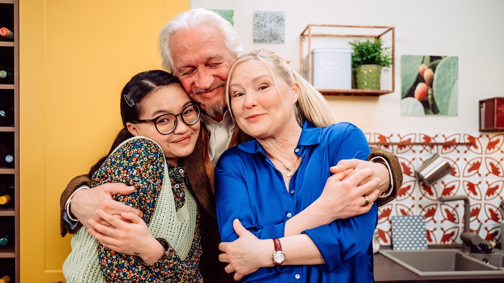 Dahoam is Dahoam: Carl (Bernd Reheuser) muss sich von seinen Mitbewohnerinnen Lien (Nui Nguyen, links) und Vera (Sybille Waury, rechts) verabschieden, um mit Annamaria auf Weltreise zu gehen. | Bildquelle: BR/Nadya Jakobs