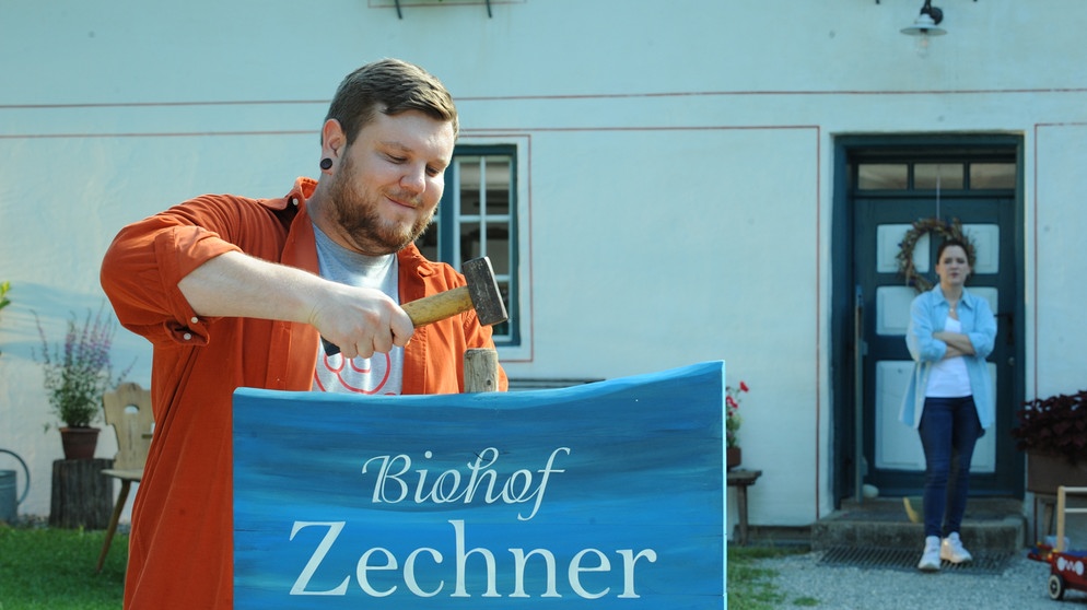 Dahoam is Dahoam: Severin (Andi Gießer) hämmert stolz das neue Bio-Hof Schild in den Boden.  | Bildquelle: BR/Marco Orlando Pichler
