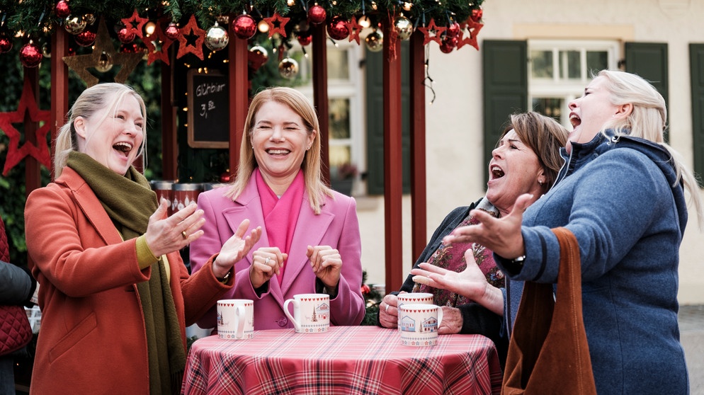 Dahoam is Dahoam: Vera, Uschi, Rosi und Ulla trällern fröhlich Veras Ohrwurm auf dem Weihnachtsmarkt. Von links: Vera (Sybille Waury), Uschi (Silke Popp), Rosi (Brigitte Walbrun, Ulla (Sabrina Dietel, KLD). | Bildquelle: BR/Lena Semmelroggen