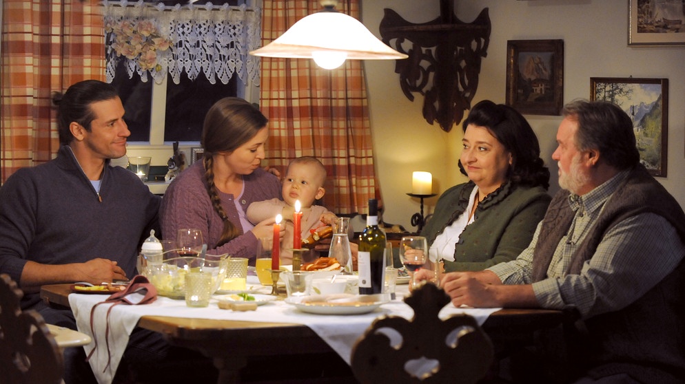Dahoam is Dahoam: Julian und Sophia sitzen gemeinsam mit Lenz, Stadlbauer und Monika am Weihnachtstisch. Von links: Julian (Sandro Kirtzel), Sophia (Patricia Freund), Monika (Christine Reimer), Stadlbauer (Andreas Geiss). | Bildquelle: BR/Marco Orlando Pichler