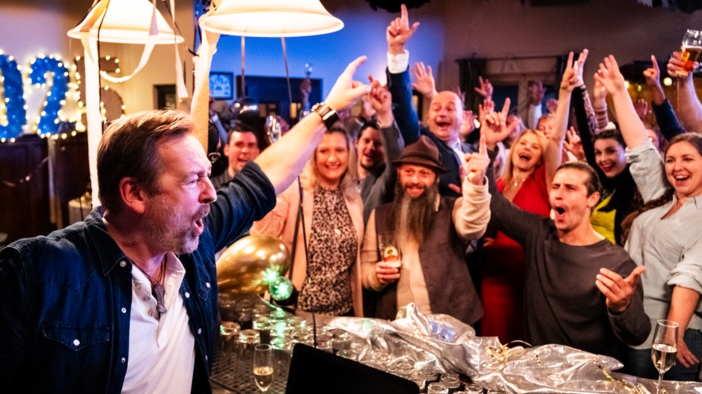 Dahoam is Dahoam: Die Lansinger feiern im Brunnerwirt Silvester. Von links: Gregor (Holger Matthias Wilhelm), Komparserie, Julian (Sandro Kirtzel), Sophia (Patricia Freund). Im Hintergrund: Hubert (Bernhard Ulrich), Uschi (Silke Popp), Tina (Anita Eichhorn) und weitere Komparserie. | Bildquelle: BR/Lena Semmelroggen