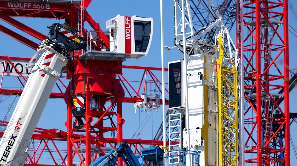 Kräne und Baumaschinen stehen auf dem Außengelände der "bauma", der weltgrößten Fachmesse für Baumaschinen, Baustoffmaschinen, Bergbaumaschinen, Baufahrzeuge und Baugeräte. Vom 07.-13.04.2025 präsentieren sich zahlreiche Hersteller auf der Messe | Bildquelle: picture alliance/dpa | Sven Hoppe
