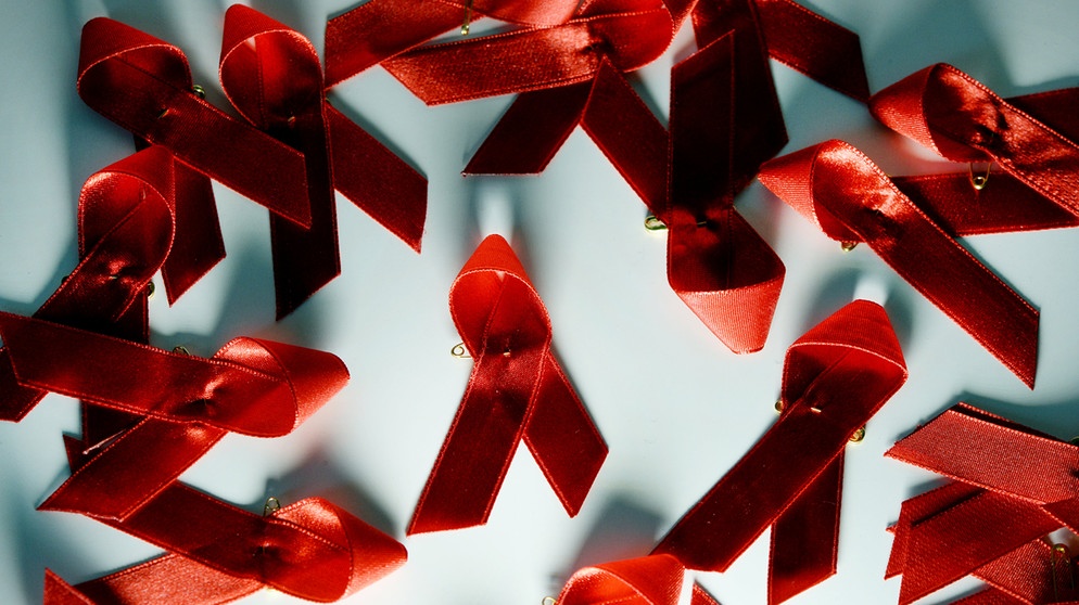 Rote Aids Schleifen liegen auf einem Tisch.  | Bildquelle: dpa-Bildfunk/Jens Kalaene