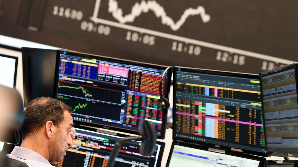 alpha-demokratie - Beflügelt Corona die Aktienmärkte? / Ein Aktienhändler beobachtet auf dem Parkett der Frankfurter Wertpapierbörse vor der Tafel mit der fallenden Dax-Kurve seine Monitore. Die sich verschärfende Corona-Krise mit schnell steigenden Infektionszahlen und einem drohenden «Lockdown» des öffentlichen Lebens in Deutschland haben den deutschen Aktienmarkt stark belastet. | Bildquelle: picture-alliance/dpa