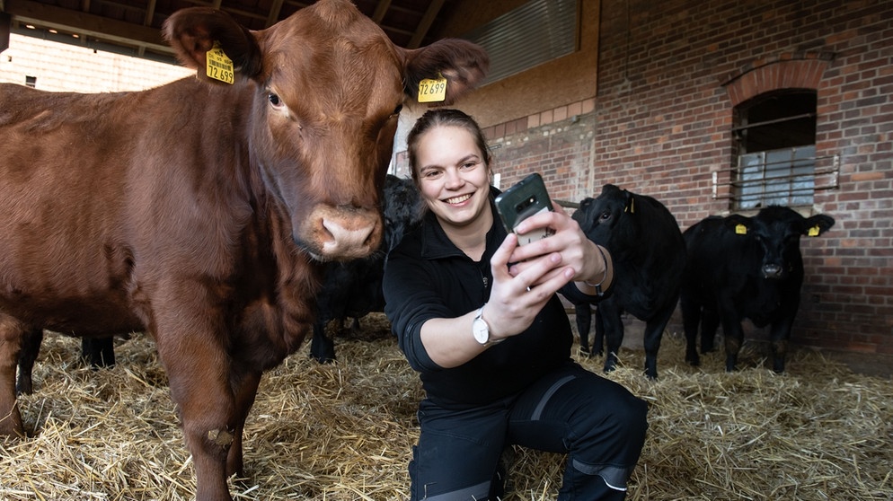 Landwirtin Ann-Christin Kahler, Influencerin, hockt mit ihrem Smartphone neben ihrem Angus-Rind "Domina" | Bildquelle: picture-alliance/dpa