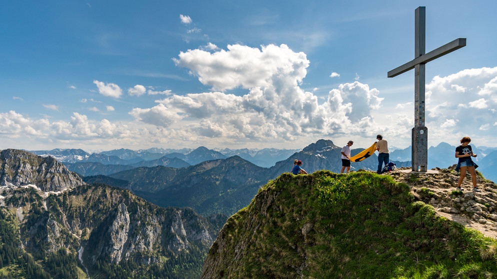 Bergsteiger stehen auf einer Bergspitze unter dem Gipfelkreuz | Bildquelle: colourbox.com / Michael Pedrotti