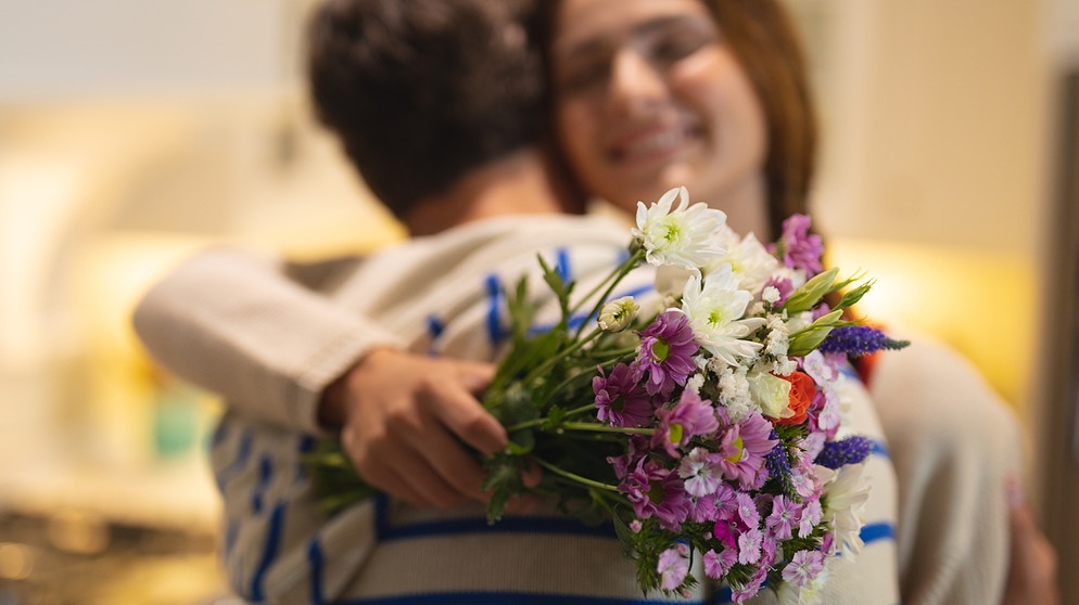 Freude! Ein junger Mann gibt einer jungen Frau einen Blumenstrauß und umarmt sie.
| Bildquelle: stock.adobe.com