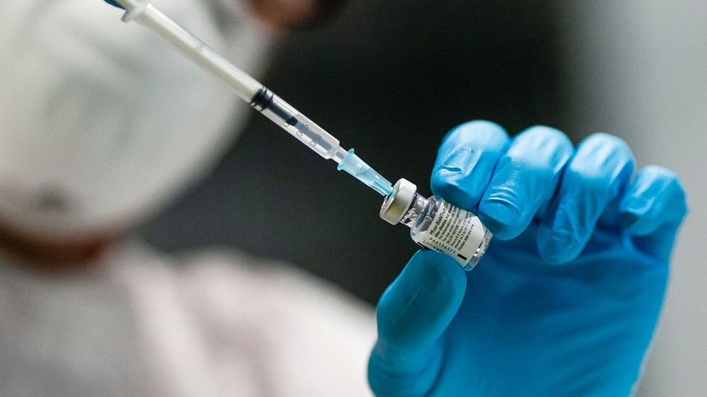 Eine Impfspritze wird von medizinischen Fachpersonal in eine Impfdose gesteckt. | Bildquelle: BR-Bild