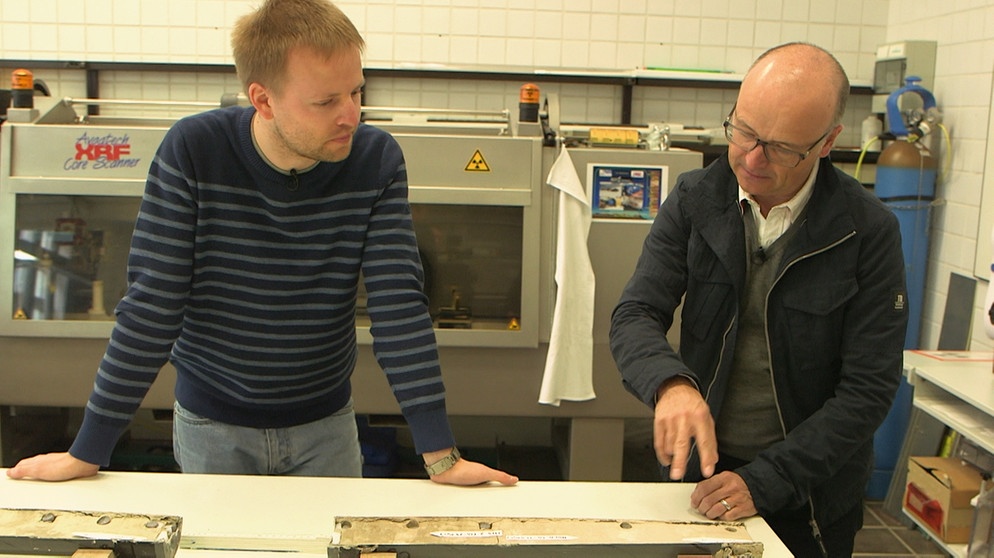 Der Geowissenschaftler Thomas Ronge (links) vom Alfred-Wegener-Institut für Polar- und Meeresforschung (AWI) bereitet Bohrkerne auf ihre Untersuchung im Labor vor. Er braucht die C-14-Datierungen von Gesine Mollenhauer dringend für seine Arbeit. Rechts: Moderator Karsten Schwanke. | Bildquelle: BR/Maximilian Schecker