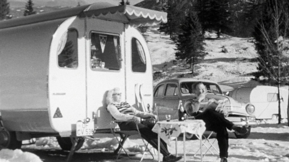 Im tiefsten Winter, wenn der normale Mensch sich bemüht, die Zimmertemperatur auf 20 Grad zu heizen, geben sich in der verschneiten Gebirgslandschaft bei Krün auf dem Campingplatz Tennsee rund 400 Camper ein Stelldichein. Das bedeutet: Morgentoilette im Freien mit kaltem Wasser, Kaffeekochen mit geschmolzenem Schnee, aber auch Schneebar, Liegestühle zum Sonnenbaden, Skifahren am Berg und Schachspielen im Wohnwagen – ein Traum in (Schwarz-)Weiß. | Bildquelle: BR