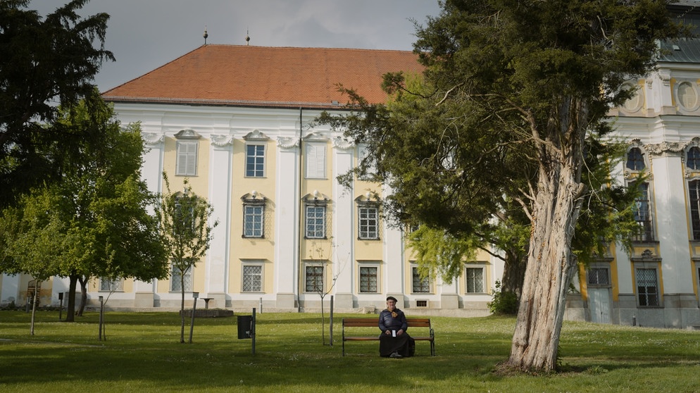 Johannes Holzinger auf einer Parkbank vor dem Kloster. | Bildquelle: ORF/BR/Tellux-Film GmbH/Metafilm GmbH