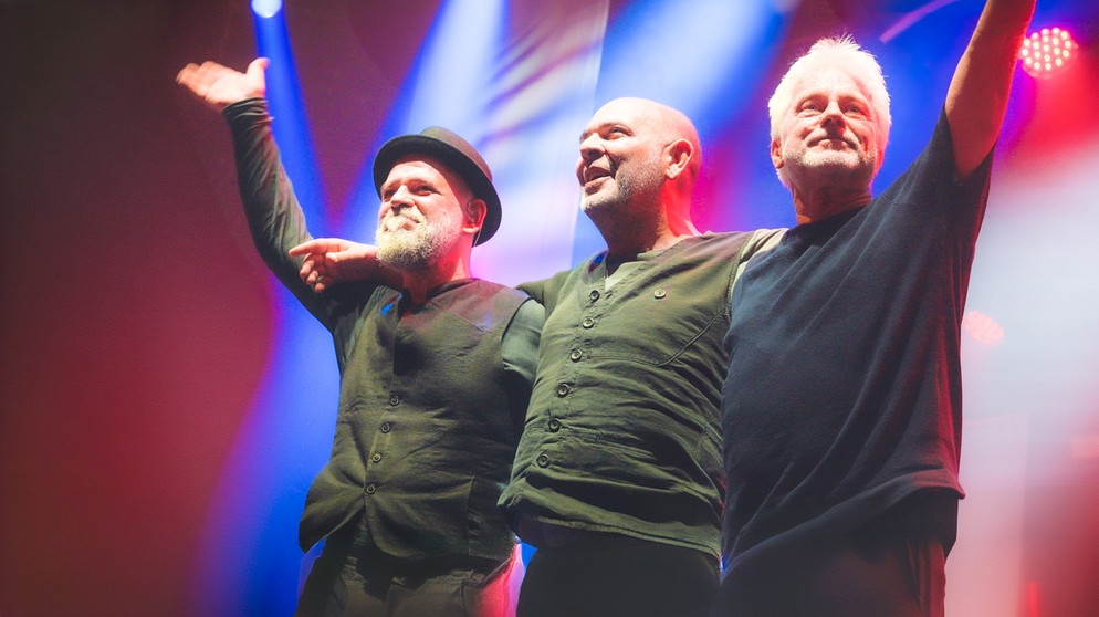 Werner Schmidbauer (rechts) und Martin Kälberer (links) freuen sich bei ihrem Auftritt auf dem Münchner Tollwood-Festival über den Besuch des niederbayerischen Musikers, Kabarettisten und Moderators Hannes Ringlstetter. | Bildquelle: Praetorius GmbH/Michael Praetorius