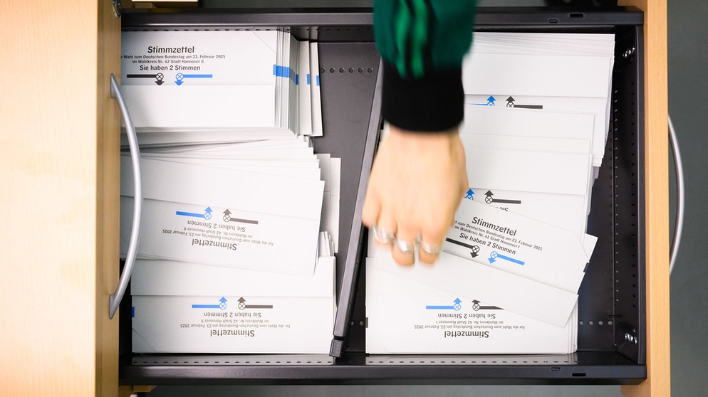 ARCHIV - 12.02.2025, Niedersachsen, Hannover: Ein Wahlhelfer nimmt in der Briefwahlstelle im Neuen Rathaus einen Stimmzettel für die Bundestagswahl 2025. (zu dpa: «Etwa 80.000 ehrenamtliche Wahlhelfer in Niedersachsen») Foto: Julian Stratenschulte/dpa +++ dpa-Bildfunk +++ | Bildquelle: dpa-Bildfunk/Julian Stratenschulte