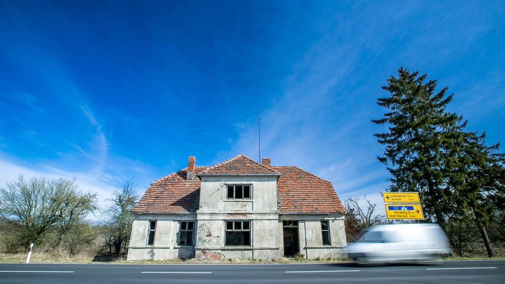 Mecklenburg-Vorpommern, Kremmin: Ein leeres und verfallenes Wohnhaus steht an der Bundesstraße 5. Nach Prognosen des Instituts der deutschen Wirtschaft (IW) wird die Bevölkerungszahl im Nordosten bis 2035 um 4,8 Prozent zurückgehen. | Bildquelle: picture alliance / Jens Büttner/dpa-Zentralbild/ZB | Jens Büttner