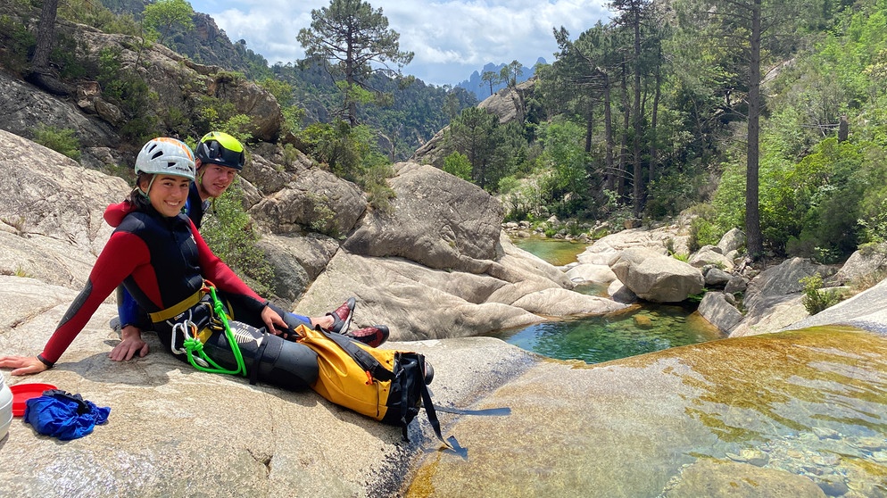 Zwei Wassersportler sitzen in einem Bachbett  | Bildquelle: BR/Michael Düchs