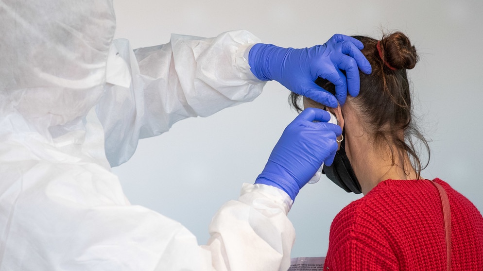 Corona-Test: BRK-Helfer misst Temperatur bei einer Frau. | Bildquelle: picture-alliance/dpa