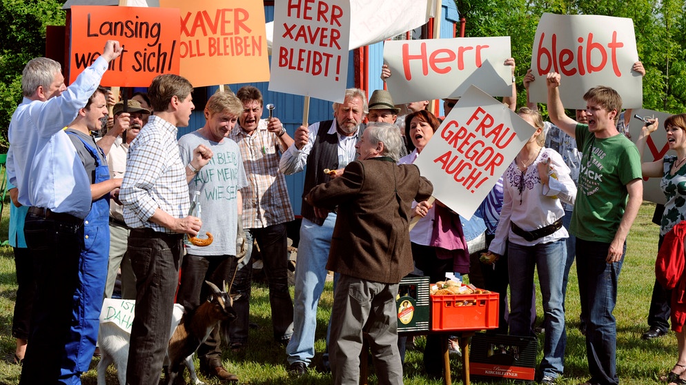Ganz Lansing demonstriert gegen Gerstl vom Landratsamt Baierkofen, damit Xaver weiter auf seiner Wiese wohnen darf. | Bildquelle: BR/Marco Orlando Pichler