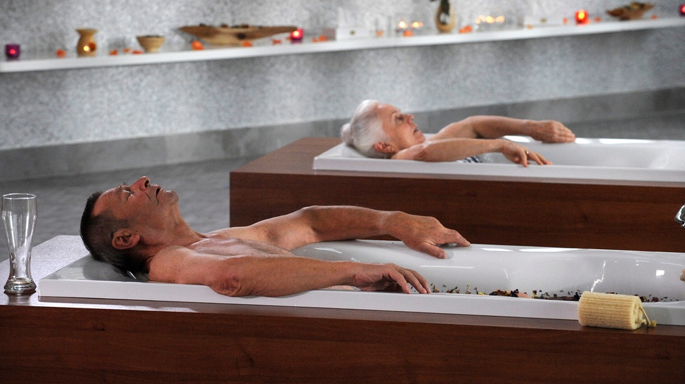 Theresa und Alois haben sich zusammengerauft und genießen nun gemeinsam die Wellness-Anwendung. Von links: Alois Preissinger (Erich Hallhuber sen.) und Theresa Brunner (Ursula Erber). | Bildquelle: BR/Marco Orlando Pichler