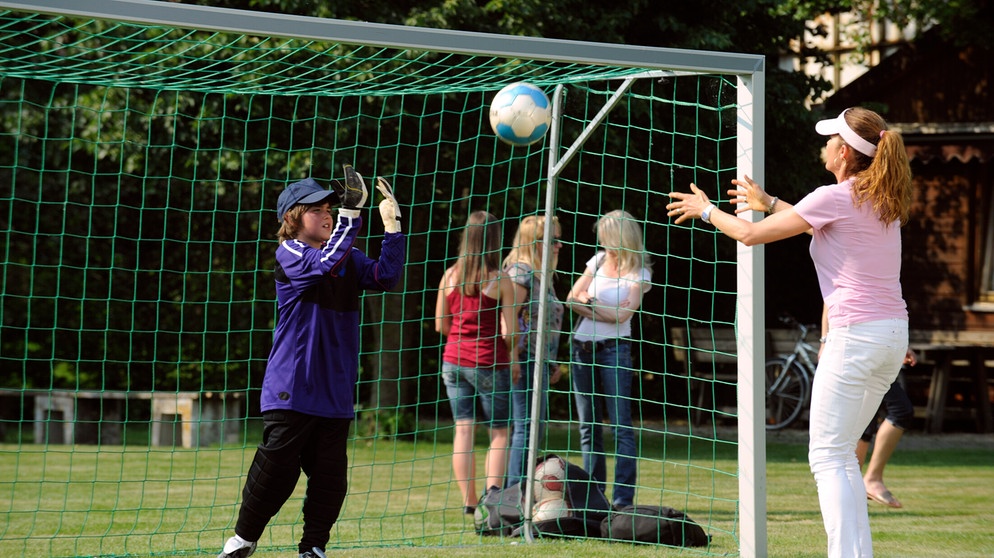 Trixi unterstützt Christian beim Aufwärmen für das anstehende Fußballspiel. Von links: Christian (Marinus Kaffl) und Trixi Preissinger (Doreen Dietel, rechts). | Bildquelle: BR/Marco Orlando Pichler