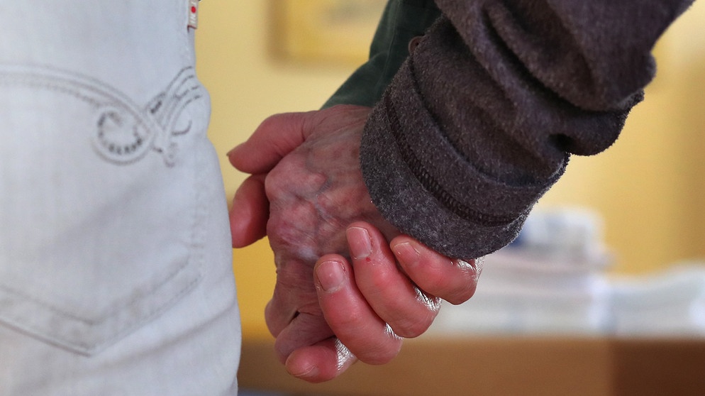 Eine Frau führt eine Bewohnerin der Demenz-Wohngemeinschaft an der Hand. | Bildquelle: dpa-Bildfunk/Karl-Josef Hildenbrand