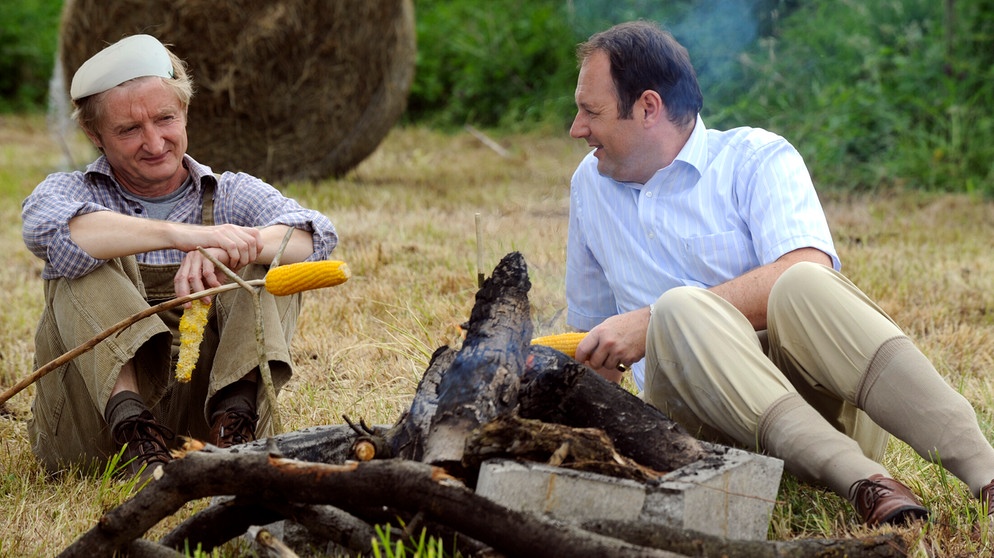 Dahoam is Dahoam. Hubert versucht in Bürgermeister Schattenhofers Auftrag, Xaver die Wiese abzuschwatzen. Von links: Xaver (Michael Schreiner) und Hubert Kirchleitner (Bernhard Ulrich). | Bildquelle: Br/Marco Orlando Pichler