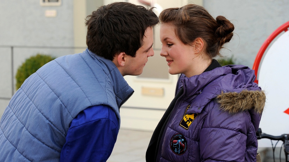 Dahoam is Dahoam. Flori küsst Sophia zur Begrüßung. Von links: Florian Brunner (Tommy Schwimmer) und Sophia (Alina Stiegler). | Bildquelle: BR/ Marco Orlando Pichler