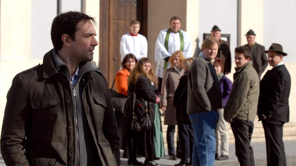 Dahoam is Dahoam: Vor der Kirche tuscheln die Lansinger über Mike (Harry Blank). | Bildquelle: BR/Marco Orlando Pichler