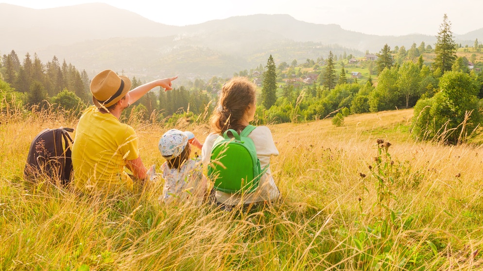 Vater, Mutter und kleines Kind ruhen sich im Gras von einer Wanderung aus.  | Bildquelle: colourbox.com