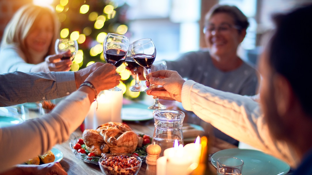 Eine Familie stößt an den Weihnachtsfeiertagen mit Rotwein an. | Bildquelle: stock.adobe.com/Krakenimages.com