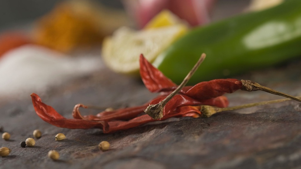 Frische Chilis - Close-up of red chili peppers with coriander seeds | Bildquelle: picture alliance / VisualEyze