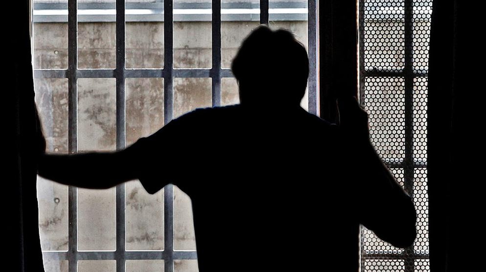 Symbolbild: Ein Mann steht vor einem vergitterten Fenster in einer Justizvollzugsanstalt | Bildquelle: dapd/Mario Vedder