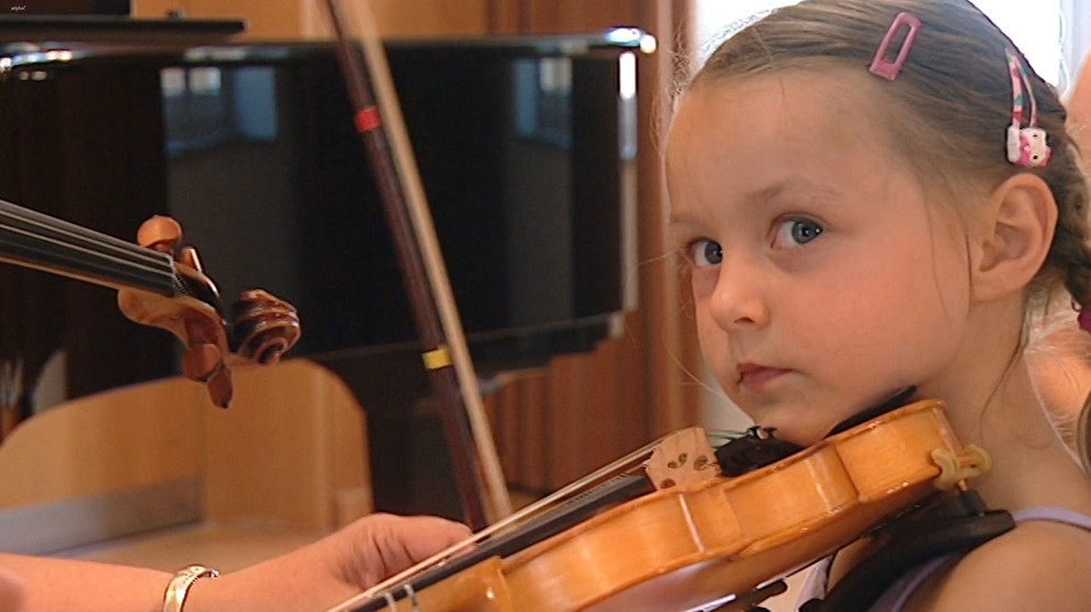 Yamina lernt in der Musikschule der Hofer Symphoniker Geige spielen. Sie bekommt gerade die richtige Haltung des Bogens gezeigt. | Bildquelle: BR