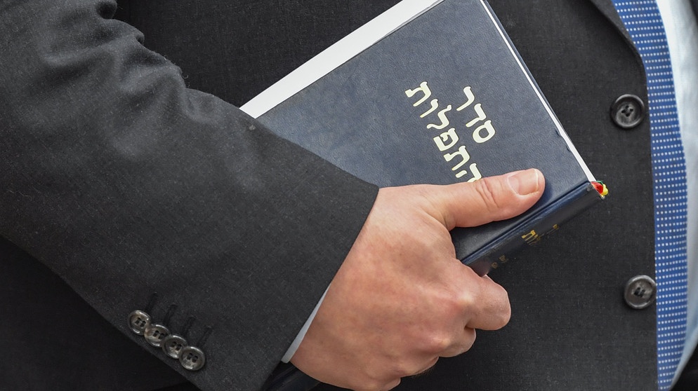 ARCHIV - 25.01.2019, Brandenburg, Cottbus: Ein Rabbi hält ein jüdisches Gebetsbuch in seiner Hand bei einer Rede an der «Bewegten Grundschule» zur feierlichen Einweihung des «Butterfly Projects».  (zu dpa: «Gebetsbuch-Fund in Aken - Rückgabe an rechtmäßigen Besitzer») Foto: Patrick Pleul/dpa-Zentralbild/dpa +++ dpa-Bildfunk +++ | Bildquelle: dpa-Bildfunk/Patrick Pleul