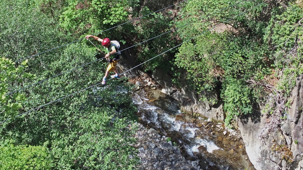 Kletterer auf seilbrücke überquert eine Schlucht | Bildquelle: BR/Pause