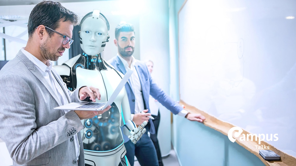 Symboldild für Campus Talks zu dem zukünftigen Umgang mit KI. Bleibt der Mensch weiterhin Chef oder wird er zum Knecht? Gleichzeitig das menschliche Gehirn im Blick(Businessmen and humanoid robot work on a project..) mit Campus Talks Logo | Bildquelle: picture alliance / Zoonar | Alexander Limbach