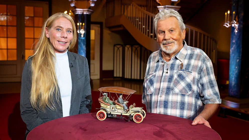 Ein großer Aufziehwagen aus Blech mit einer kaiserlichen Insassin. Das Expertenteam in der Musikhalle Ludwigsburg staunt, der Gast freut sich über den Wert. Dazu ein filigraner Armreif aus Gold und eine Kirche in seltsamer Umgebung. | Bildquelle: BR/Ralf Wilschewski