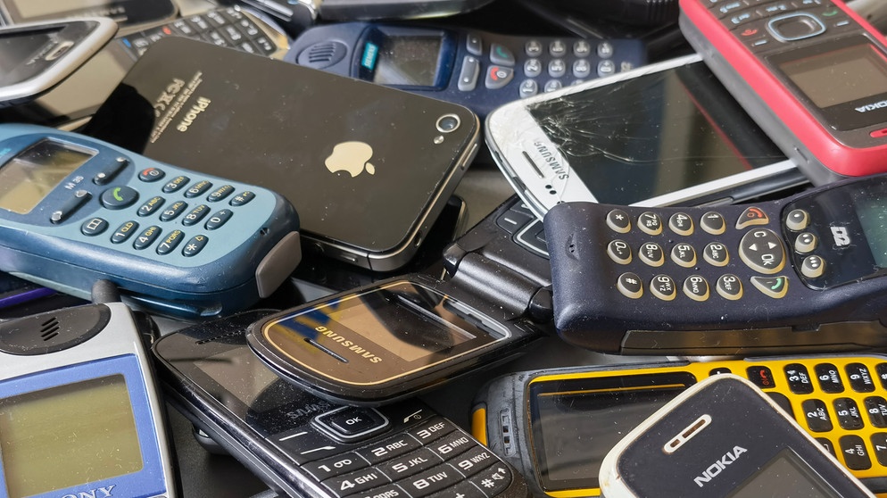 Ausrangierte Mobiltelefone liegen auf einem Tisch. Nach Angaben des Digitalverbandes Bitkom bewahren die Menschen in Deutschland über 200 Millionen Handys und Smartphones zu Hause auf (Stand: März 2021) | Bildquelle: picture alliance/dpa | Christoph Dernbach