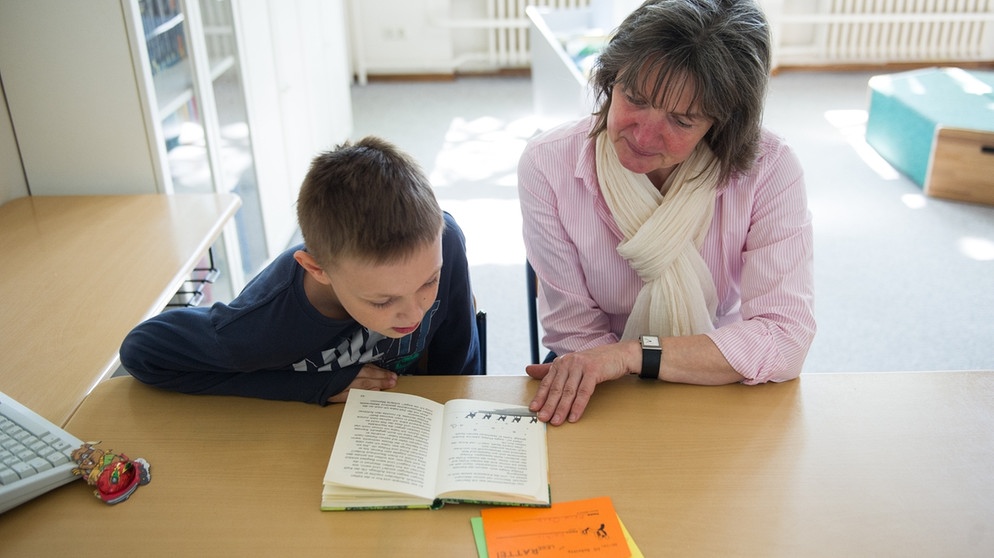 Die Mentorin Anja Osen und der Schüler Dustin Grabowski lesen in der Grundschule Furtweg in Hamburg ein Buch. Ein Mal pro Woche treffen sich die Mentoren des Vereins «Mentor Hamburg e.V.» mit ihren Lesepaten zum Üben. | Bildquelle: Maja Hitij/dpa