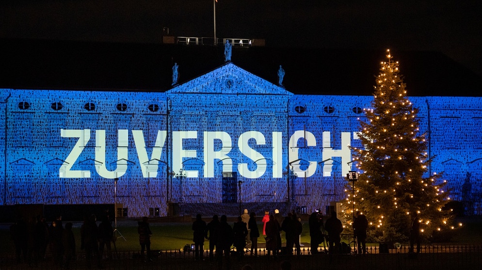 dpatopbilder - 15.12.2020, Berlin: Bundespräsident Frank-Walter Steinmeier und seine Frau Elke Büdenbender schauen sich an, wie zahlreiche Bilder und Botschaften zum Start des Projekts "Lichtblick" auf die Fassade von Schloss Bellevue projiziert werden. Vom 15. bis 17.12.2020 wird die Fassade von Schloss Bellevue mit einer künstlerischen Lichtprojektion angestrahlt, bei der Botschaften gezeigt werden, die Menschen aus ganz Deutschland eingeschickt haben. Mit dem "Lichtblick" möchte Bundespräsident Steinmeier am Ende dieses besonderen, durch die Corona-Pandemie geprägten Jahres ein Zeichen der Ermutigung und des Zusammenhalts setzen. Foto: Bernd von Jutrczenka/dpa +++ dpa-Bildfunk +++ | Bildquelle: dpa-Bildfunk/Bernd von Jutrczenka
