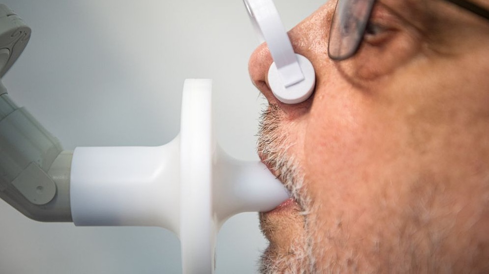 Ein Long-Covid-Patient bläst bei einem Lungenbelastungstest in ein Rohr. | Bildquelle: dpa-Bildfunk/Sina Schuldt